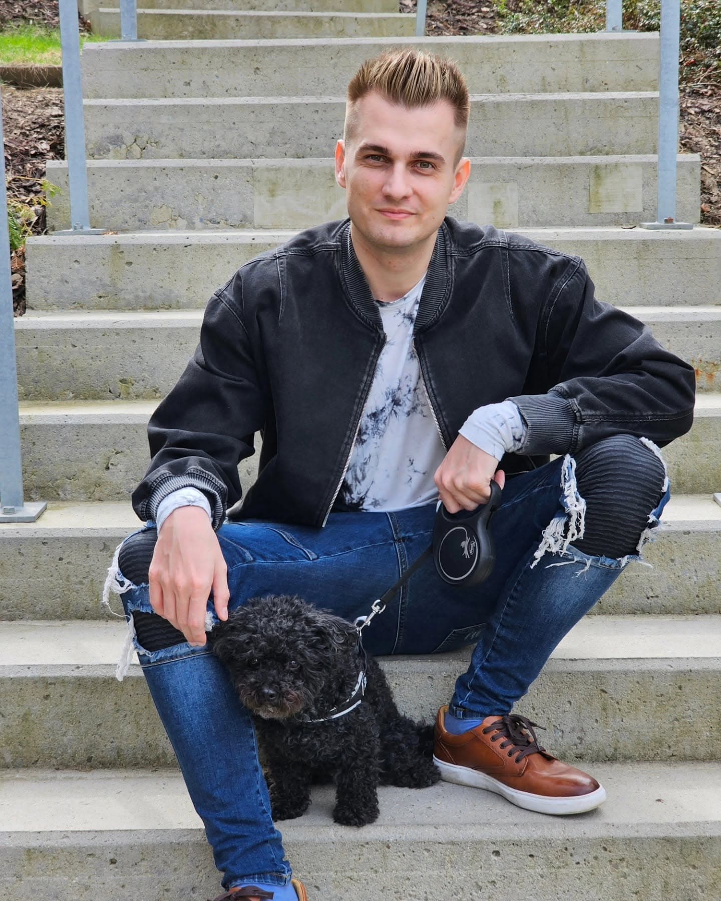 Filip Trubelík, lektor angličtiny, sedící na schodech se svým psem